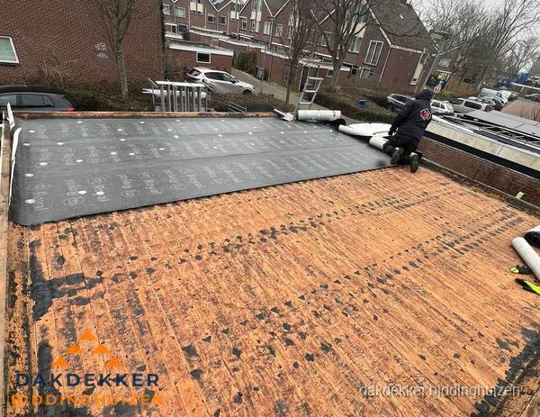 Dakdekker legt onderlaag op plat dak met houten constructie in Biddinghuizen