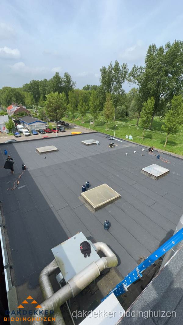 Dakdekker aan het werk op groot plat dak met bitumen in Biddinghuizen