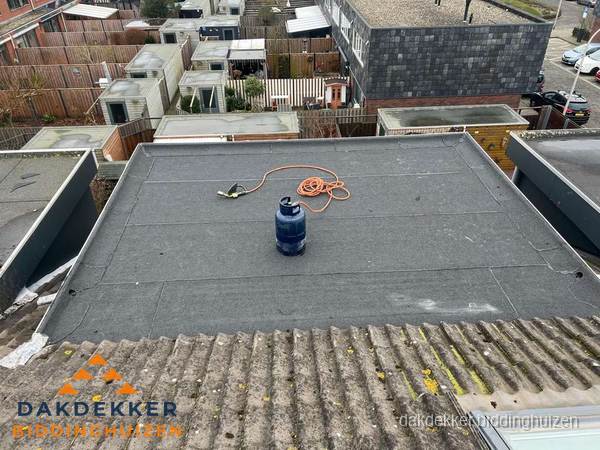 Plat dak met nieuwe bitumen dakbedekking en brandgereedschap in Biddinghuizen