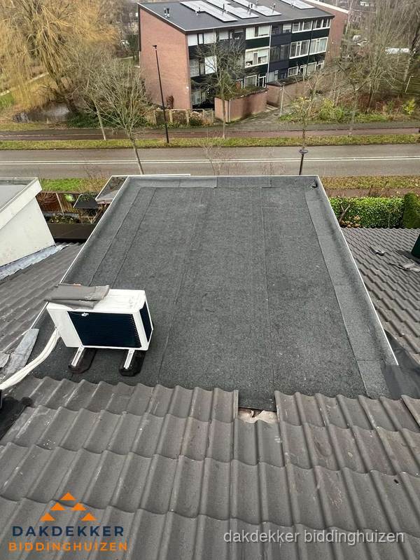Plat dak inspectie met bitumen bedekking naast schuin pannendak in Biddinghuizen