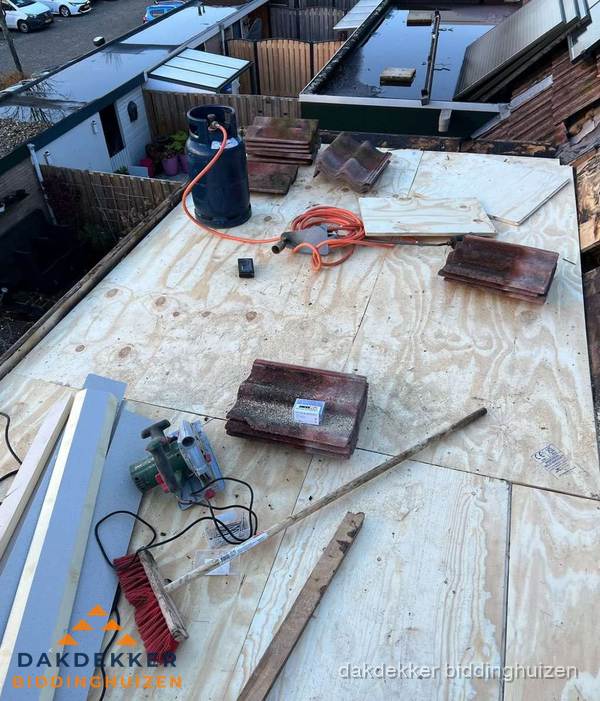 Dakreparatie werkzaamheden op plat dak met gereedschap in Biddinghuizen