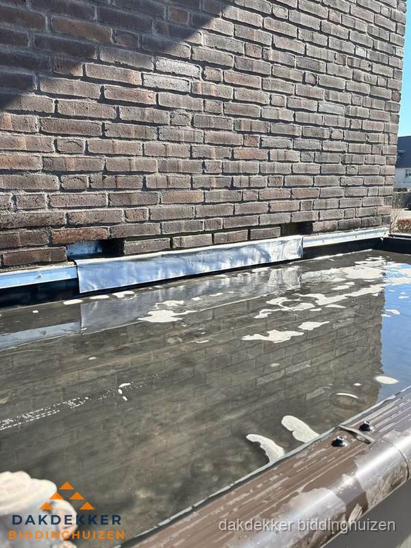 Stilstaand water op plat dak door slechte afwatering in Biddinghuizen