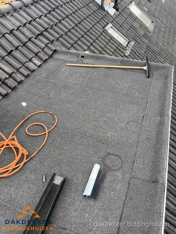 Plat dak reparatie met gereedschap en loodstroken in Biddinghuizen