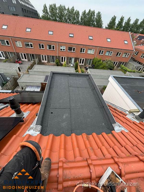 Bitumen dak reparatie op plat dak tussen dakpannen in Biddinghuizen