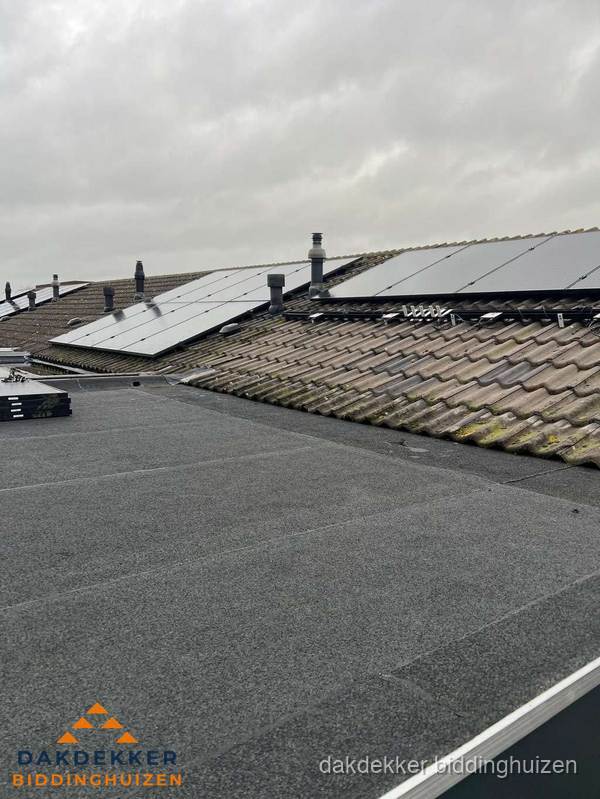 Bitumen dakbedekking op plat dak met aansluitend pannendak en zonnepanelen in Biddinghuizen