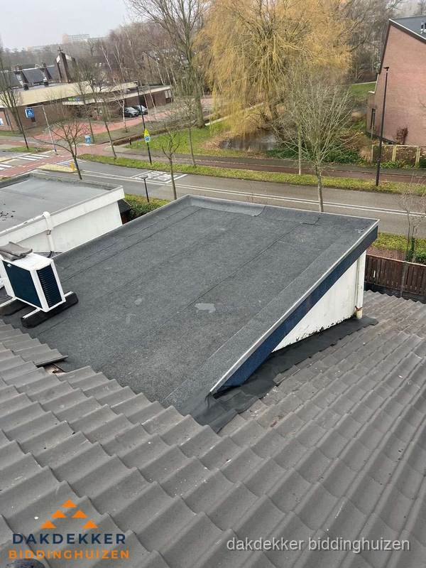 Plat dak met bitumen dakbedekking naast schuin pannendak in Biddinghuizen