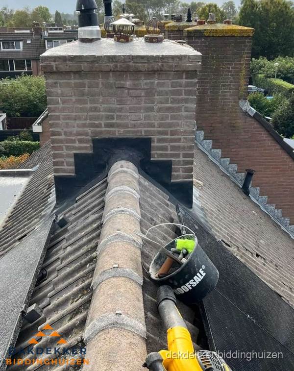Schoorsteen met loodaansluiting en nokvorst op pannendak in Biddinghuizen