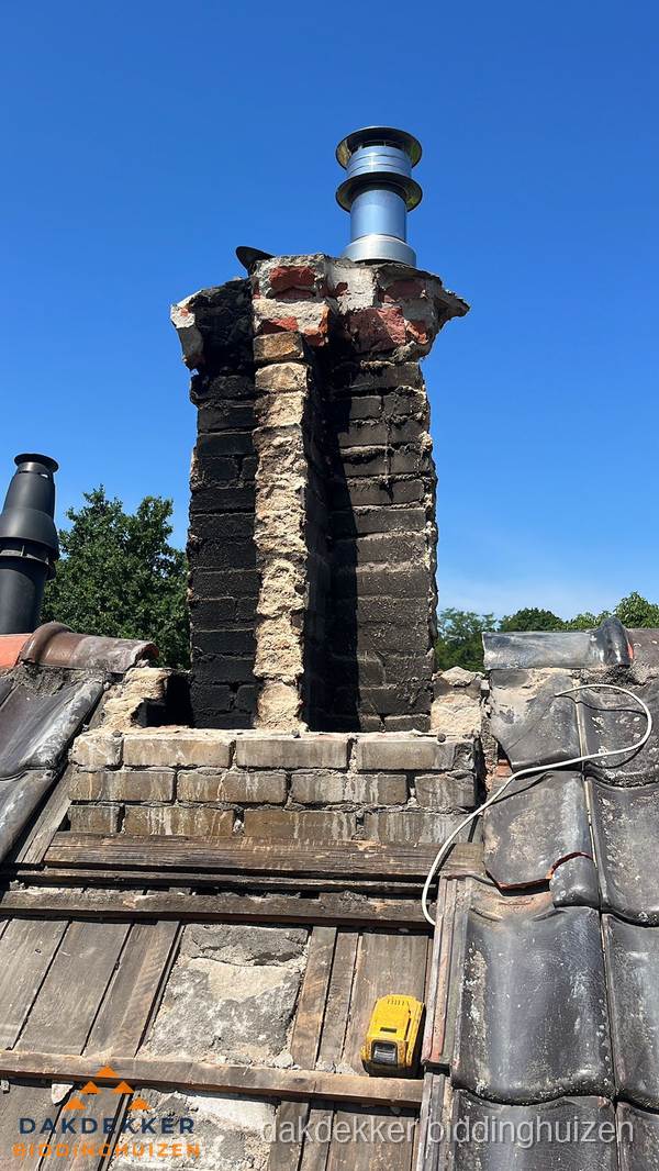 Beschadigde schoorsteen met nieuwe rookgasafvoer op oud dak in Biddinghuizen