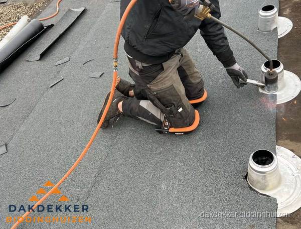 Dakdekker repareert bitumen dakleer bij dakdoorvoer in Biddinghuizen