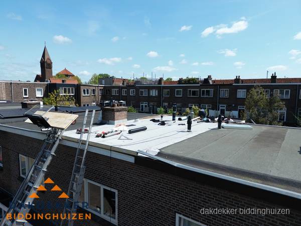 Dakdekkers aan het werk op plat dak in Biddinghuizen