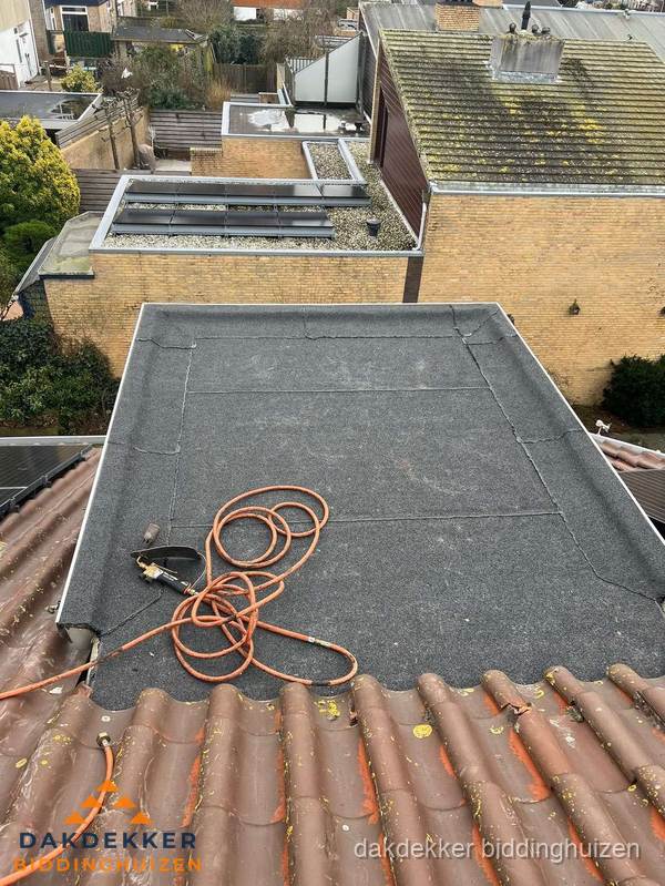 Reparatie aansluiting plat dak en schuin dak in Biddinghuizen